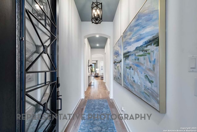 hall featuring wood-type flooring and a chandelier