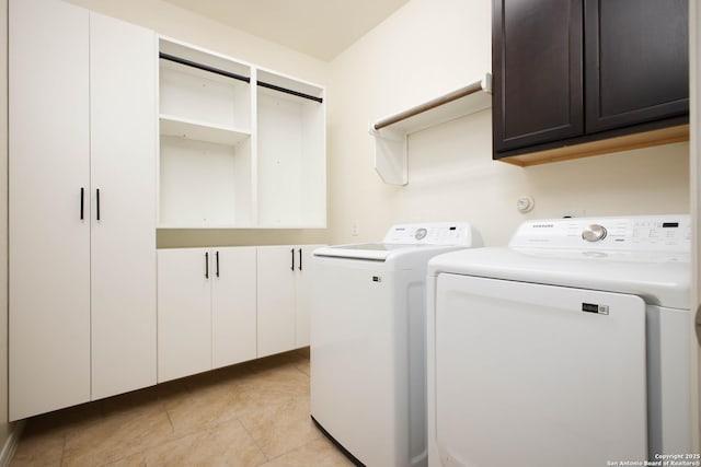 laundry area with light tile patterned floors, washer and clothes dryer, and cabinets