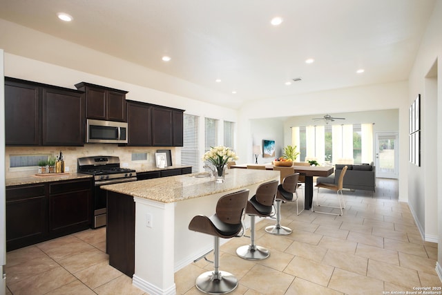 kitchen featuring a breakfast bar area, backsplash, a center island, light stone counters, and stainless steel appliances