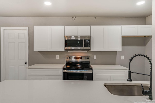 kitchen with stainless steel appliances, sink, and white cabinets