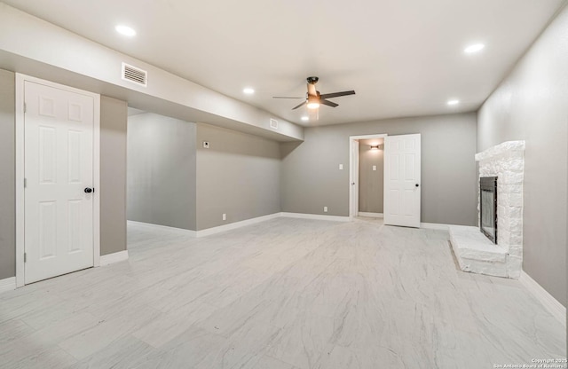 unfurnished living room with a stone fireplace and ceiling fan