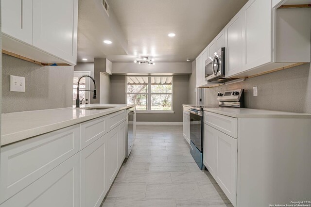 kitchen with tasteful backsplash, sink, stainless steel appliances, and white cabinets