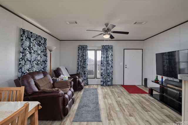 living room with crown molding, ceiling fan, and light wood-type flooring