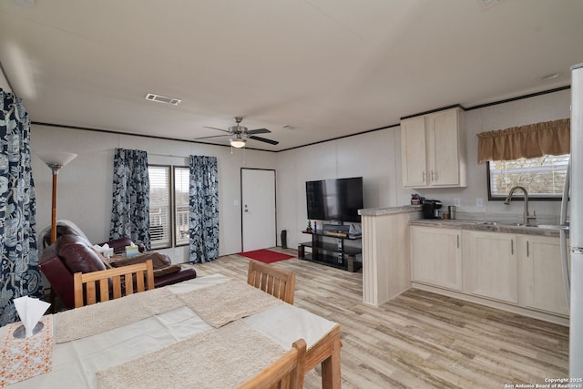 dining space with ceiling fan, light hardwood / wood-style floors, sink, and a wealth of natural light