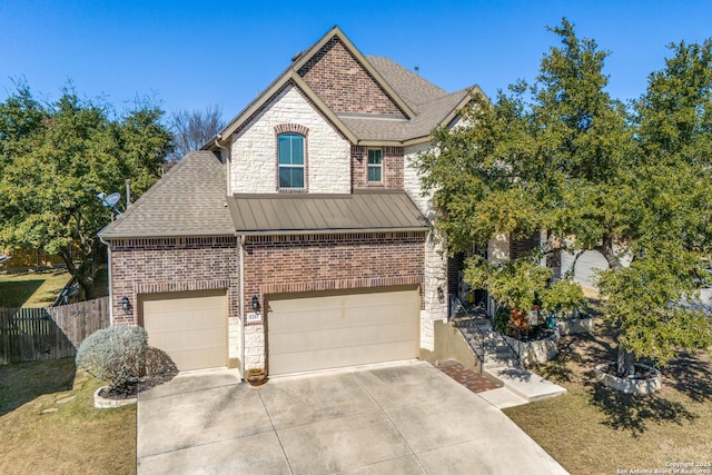 french country home featuring driveway, stone siding, fence, roof with shingles, and metal roof