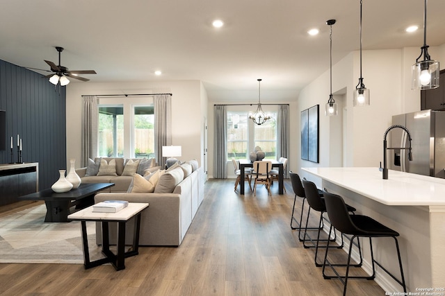 living room featuring plenty of natural light, ceiling fan with notable chandelier, and light wood-type flooring