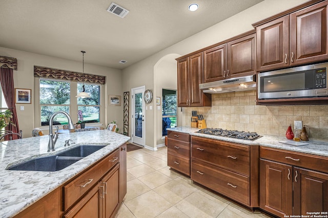 kitchen with light stone countertops, appliances with stainless steel finishes, sink, and backsplash