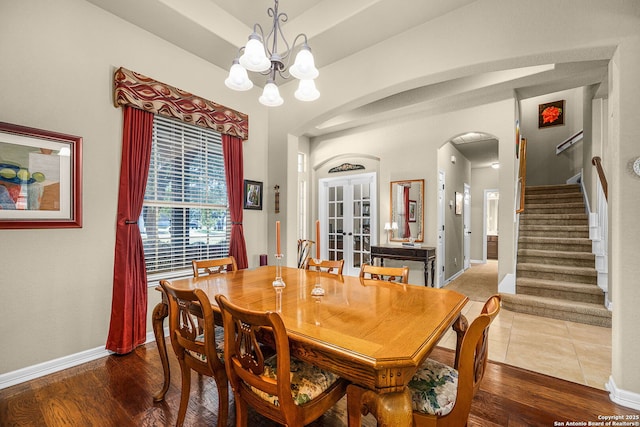 dining area with french doors, wood-type flooring, a tray ceiling, and an inviting chandelier