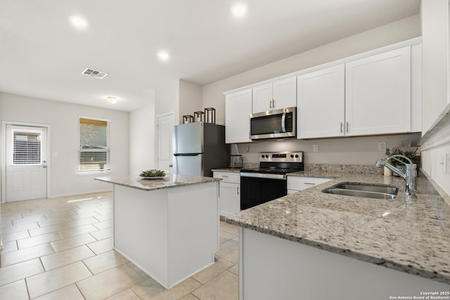 kitchen with a kitchen island, white cabinetry, appliances with stainless steel finishes, and sink