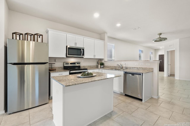 kitchen with sink, a kitchen island, white cabinets, and appliances with stainless steel finishes