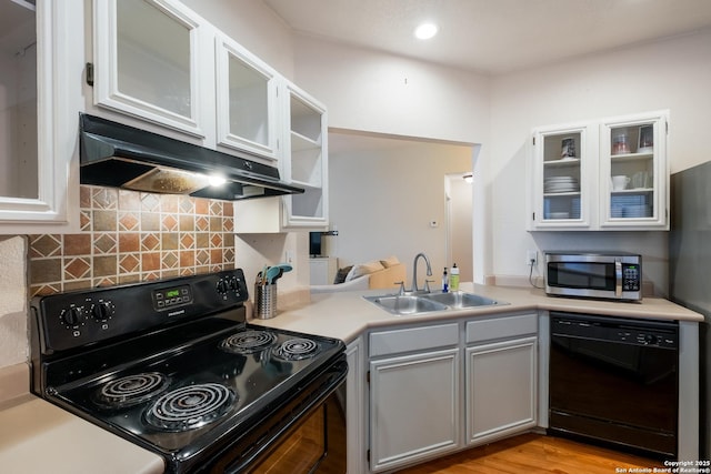 kitchen with black appliances, sink, backsplash, light hardwood / wood-style floors, and kitchen peninsula