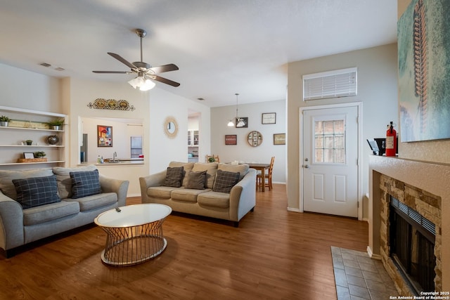 living room featuring a tiled fireplace, wood-type flooring, vaulted ceiling, and ceiling fan