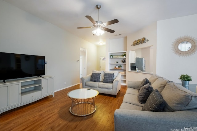 living room with ceiling fan, light hardwood / wood-style floors, and built in features