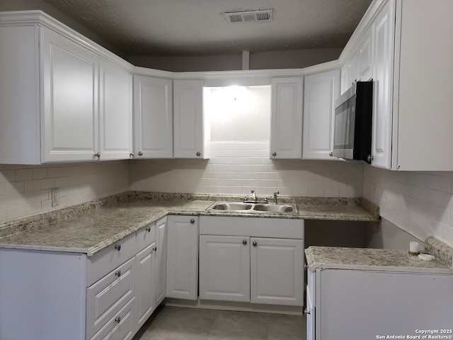 kitchen with sink, decorative backsplash, light tile patterned floors, and white cabinets