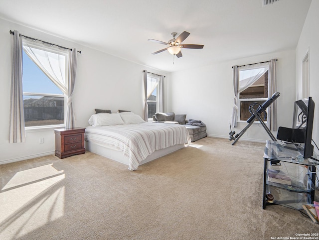 bedroom with ceiling fan, light carpet, and multiple windows