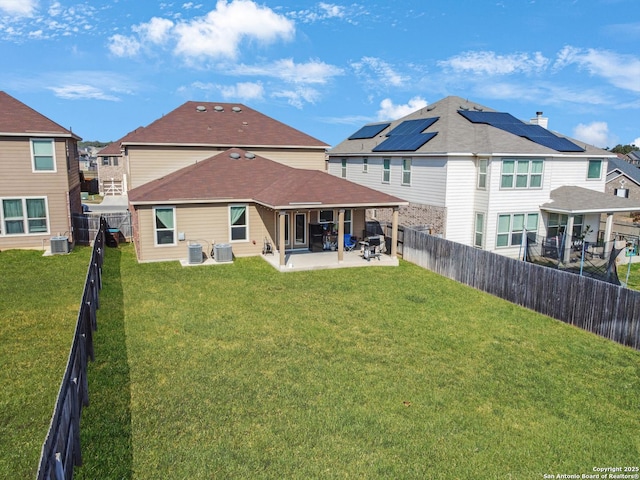 rear view of property with cooling unit, a yard, a patio area, and solar panels