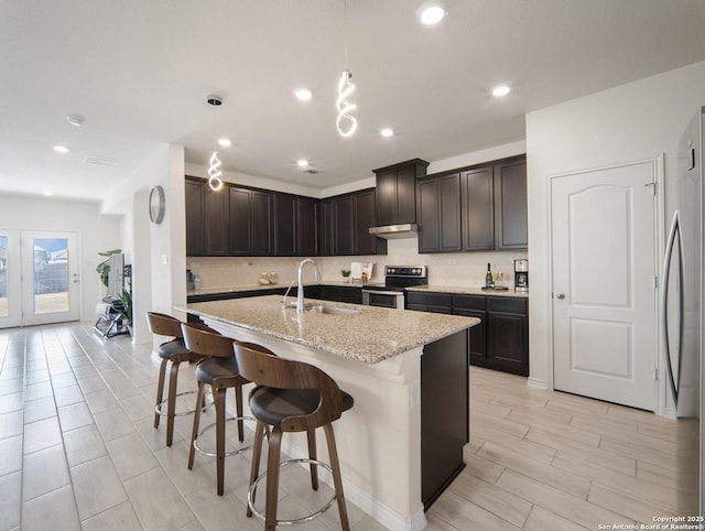 kitchen featuring appliances with stainless steel finishes, pendant lighting, sink, backsplash, and light stone counters