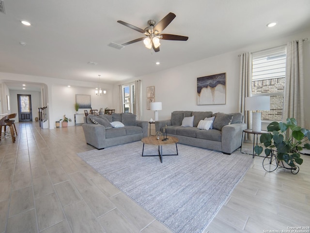 living room featuring ceiling fan with notable chandelier and light hardwood / wood-style floors