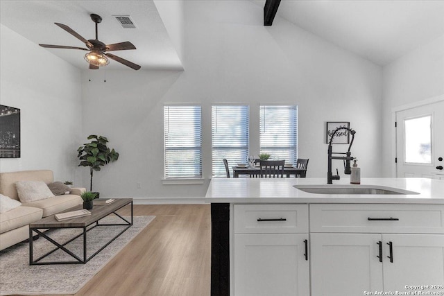 kitchen featuring sink, light hardwood / wood-style flooring, high vaulted ceiling, and white cabinets