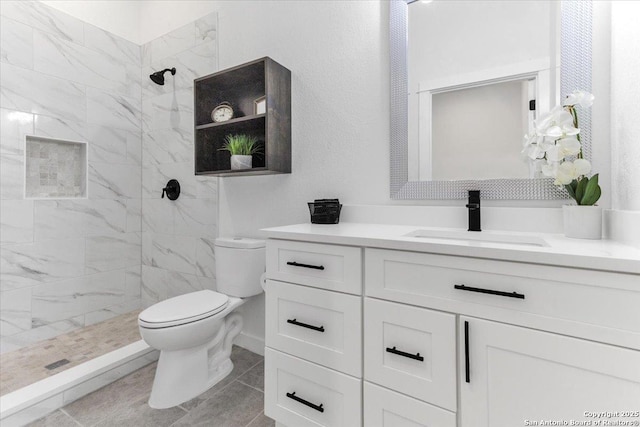 bathroom featuring vanity, toilet, and a tile shower