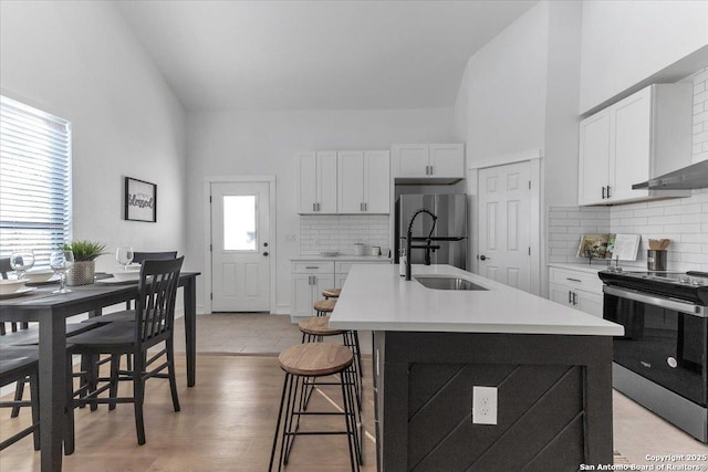 kitchen featuring sink, a breakfast bar, a kitchen island with sink, stainless steel appliances, and white cabinets