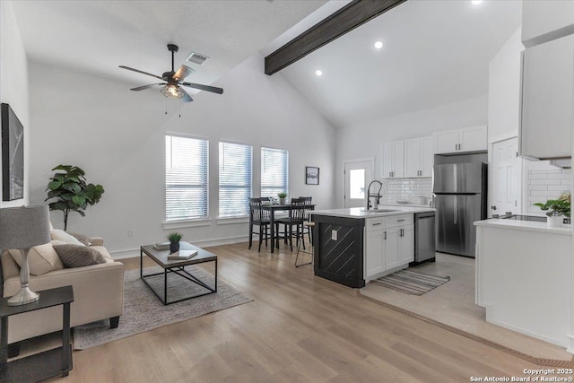 living room featuring high vaulted ceiling, sink, light wood-type flooring, ceiling fan, and beam ceiling