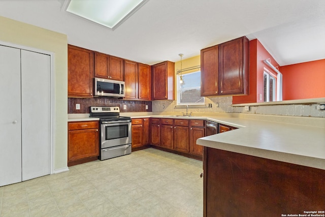 kitchen with appliances with stainless steel finishes, sink, pendant lighting, and backsplash