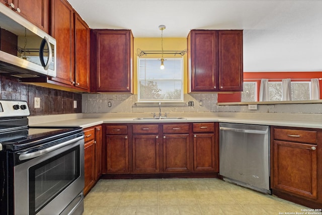 kitchen featuring tasteful backsplash, appliances with stainless steel finishes, sink, and hanging light fixtures