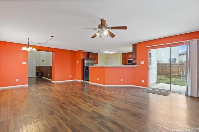 unfurnished living room with dark hardwood / wood-style flooring and ceiling fan with notable chandelier