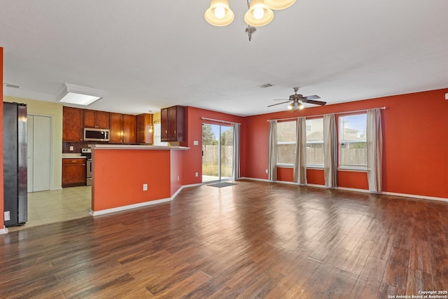 unfurnished living room with dark hardwood / wood-style floors and ceiling fan with notable chandelier