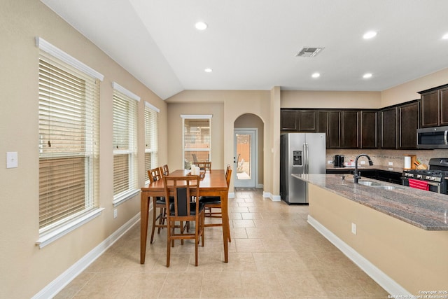 kitchen with light stone counters, appliances with stainless steel finishes, sink, and dark brown cabinets