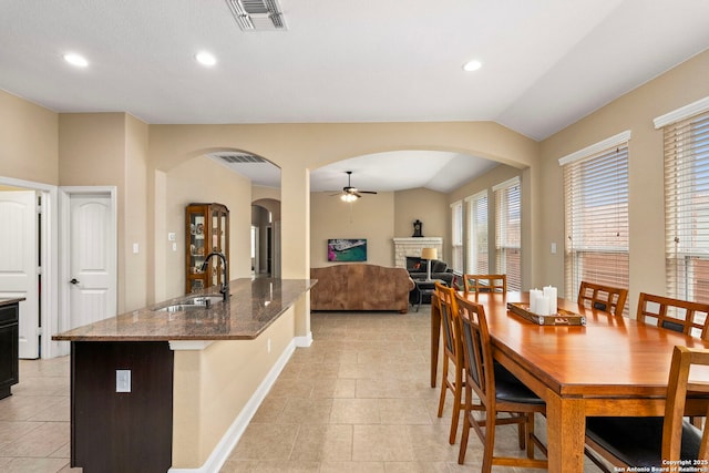 tiled dining area with lofted ceiling, sink, and ceiling fan