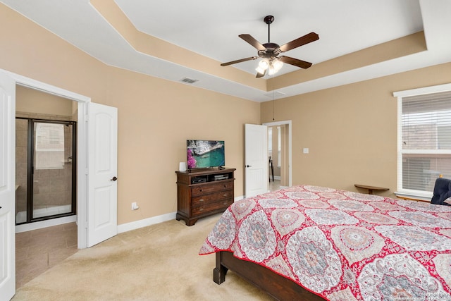 carpeted bedroom with a tray ceiling and ceiling fan