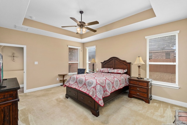 carpeted bedroom featuring ceiling fan and a raised ceiling