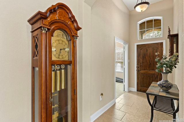 foyer entrance with a baseboard heating unit and a towering ceiling