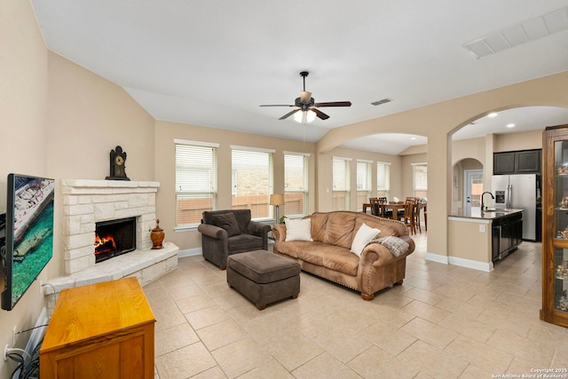 tiled living room featuring ceiling fan, a fireplace, and a healthy amount of sunlight