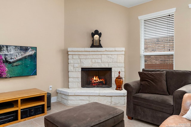 living room featuring light tile patterned floors and a stone fireplace