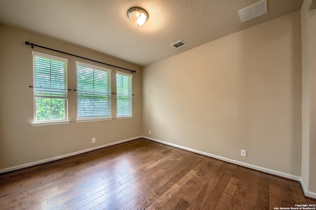 empty room featuring wood-type flooring and a textured ceiling