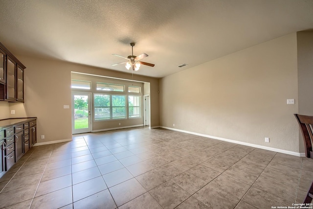 unfurnished living room with light tile patterned floors, a textured ceiling, and ceiling fan