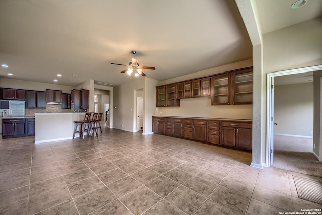 kitchen with light tile patterned floors, decorative backsplash, a breakfast bar, and ceiling fan