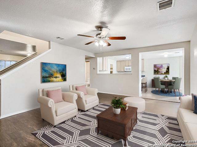 living room with ceiling fan, wood-type flooring, and a textured ceiling