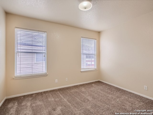 carpeted spare room featuring a textured ceiling