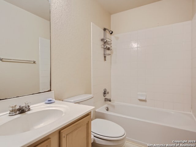 full bathroom featuring vanity, tiled shower / bath combo, and toilet