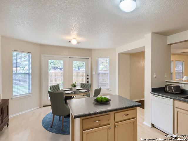 kitchen with a textured ceiling, light hardwood / wood-style floors, a center island, and dishwasher