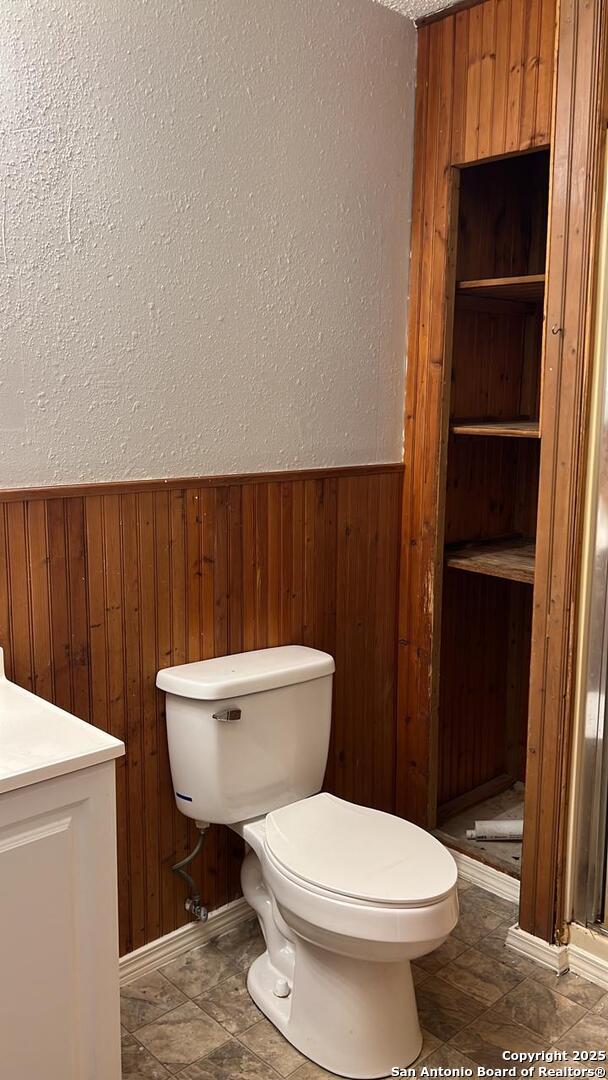 bathroom featuring vanity, toilet, and wood walls