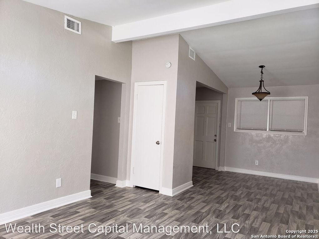 unfurnished room featuring dark wood-type flooring and vaulted ceiling with beams