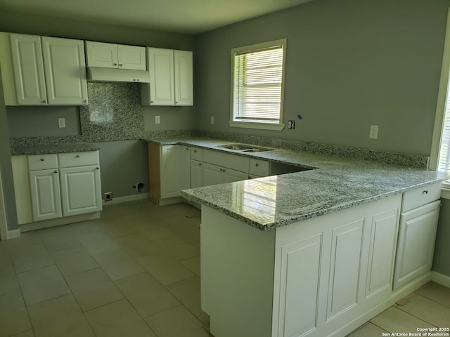 kitchen featuring sink, white cabinetry, light stone counters, decorative backsplash, and kitchen peninsula