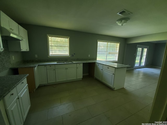 kitchen with french doors, kitchen peninsula, sink, and white cabinets