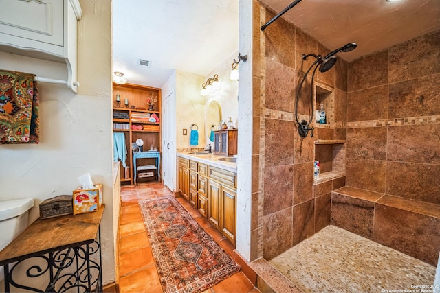 bathroom with vanity, tiled shower, and tile patterned floors