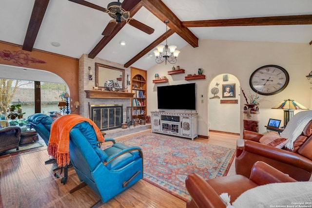 living room with hardwood / wood-style flooring, vaulted ceiling with beams, ceiling fan with notable chandelier, and a fireplace